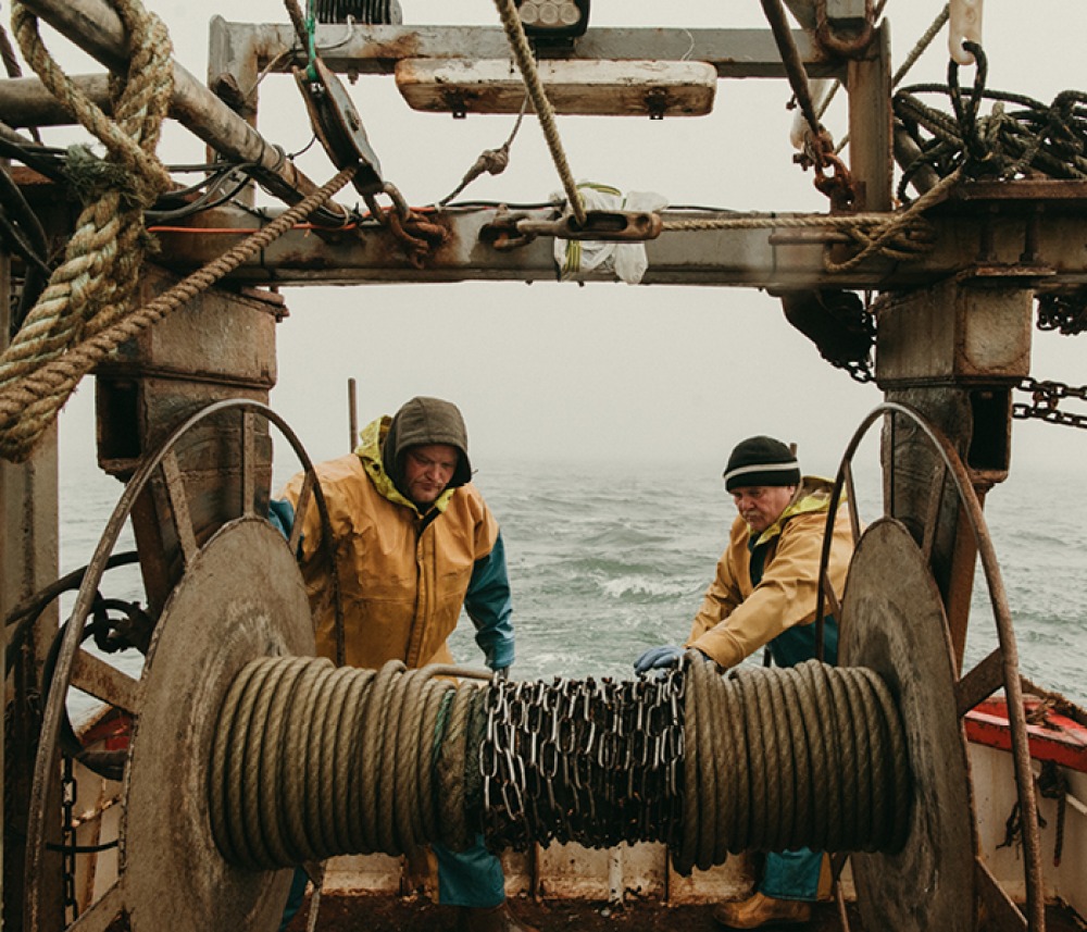 Fishermen pulling in lines dressed in yellows at the rear of a boat