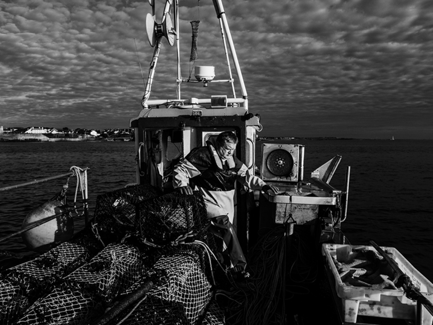 black and white image of a fisherman standing on his boat