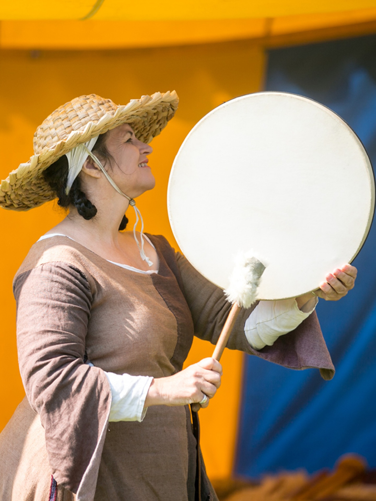Woman in historic dress plating a drum