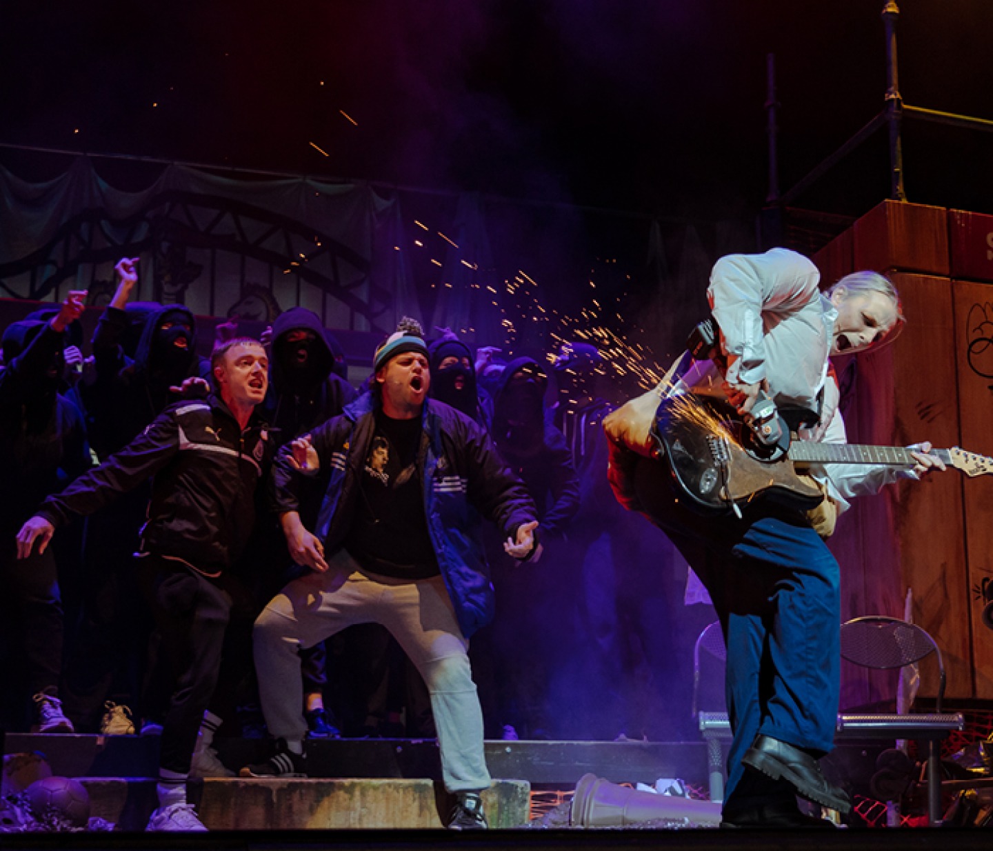 Gerry and Sewell behind a woman damaging a guitar with electric tool