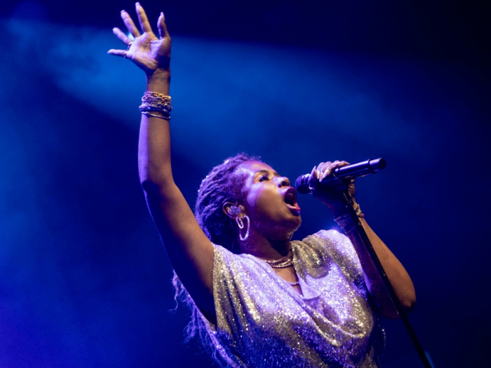 Kelis singing with her hand in the air