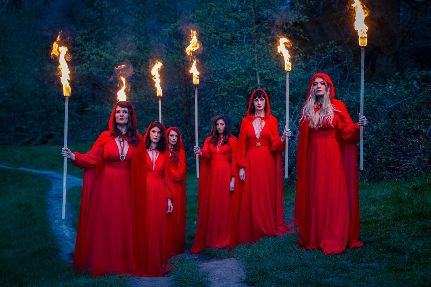 The Mediaeval Baebes wearing red hooded cloaks holding a burning torch
