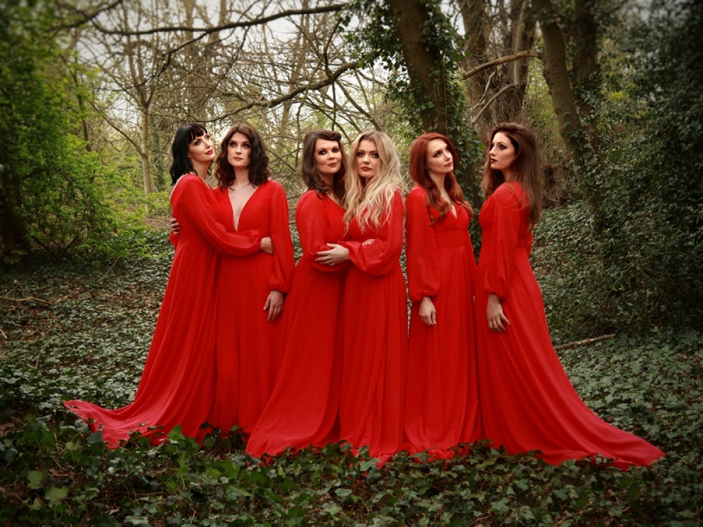 The Mediaeval Baebes dressed in red standing in a forrest