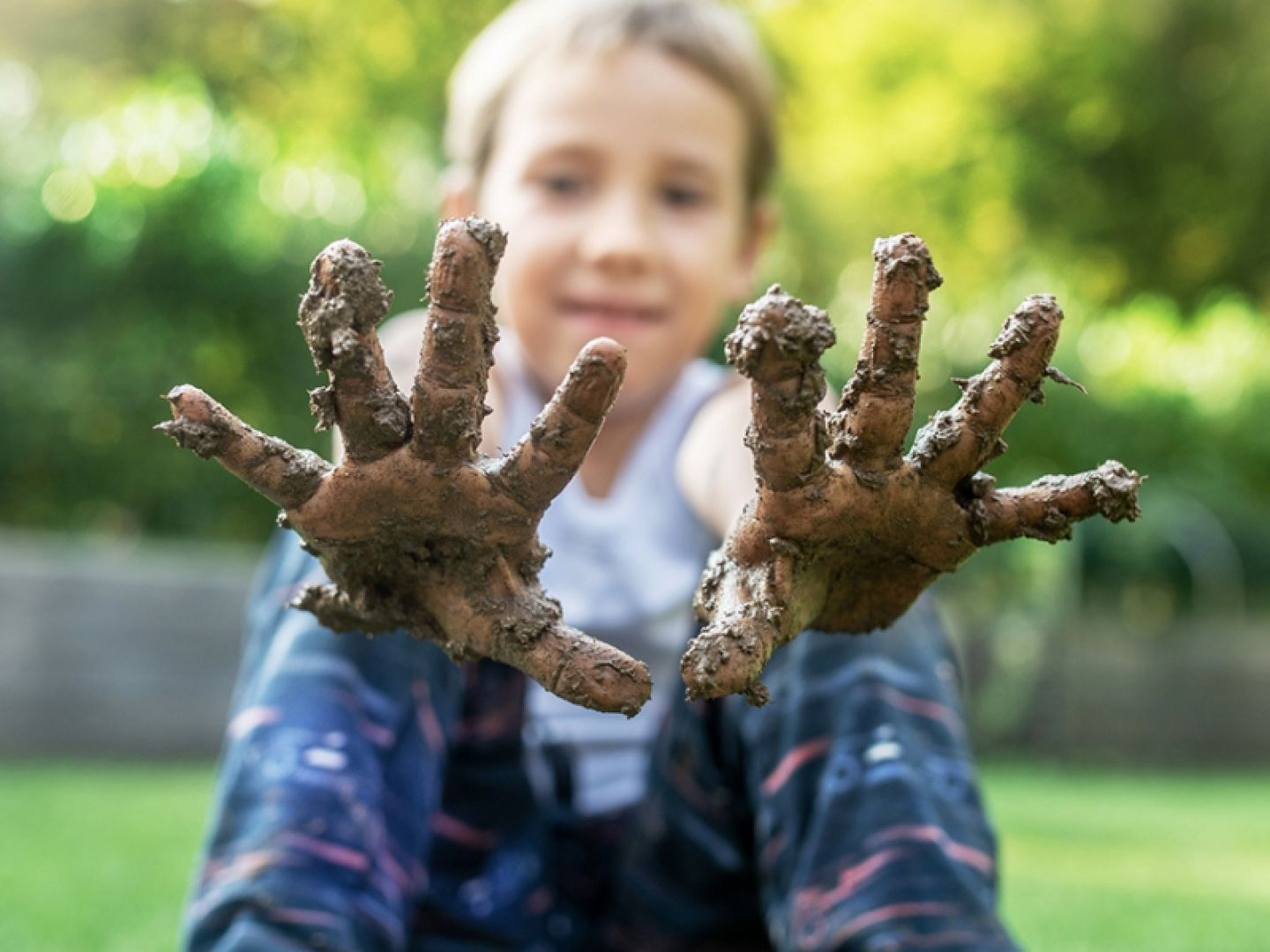 a child with mud on their hands smiling