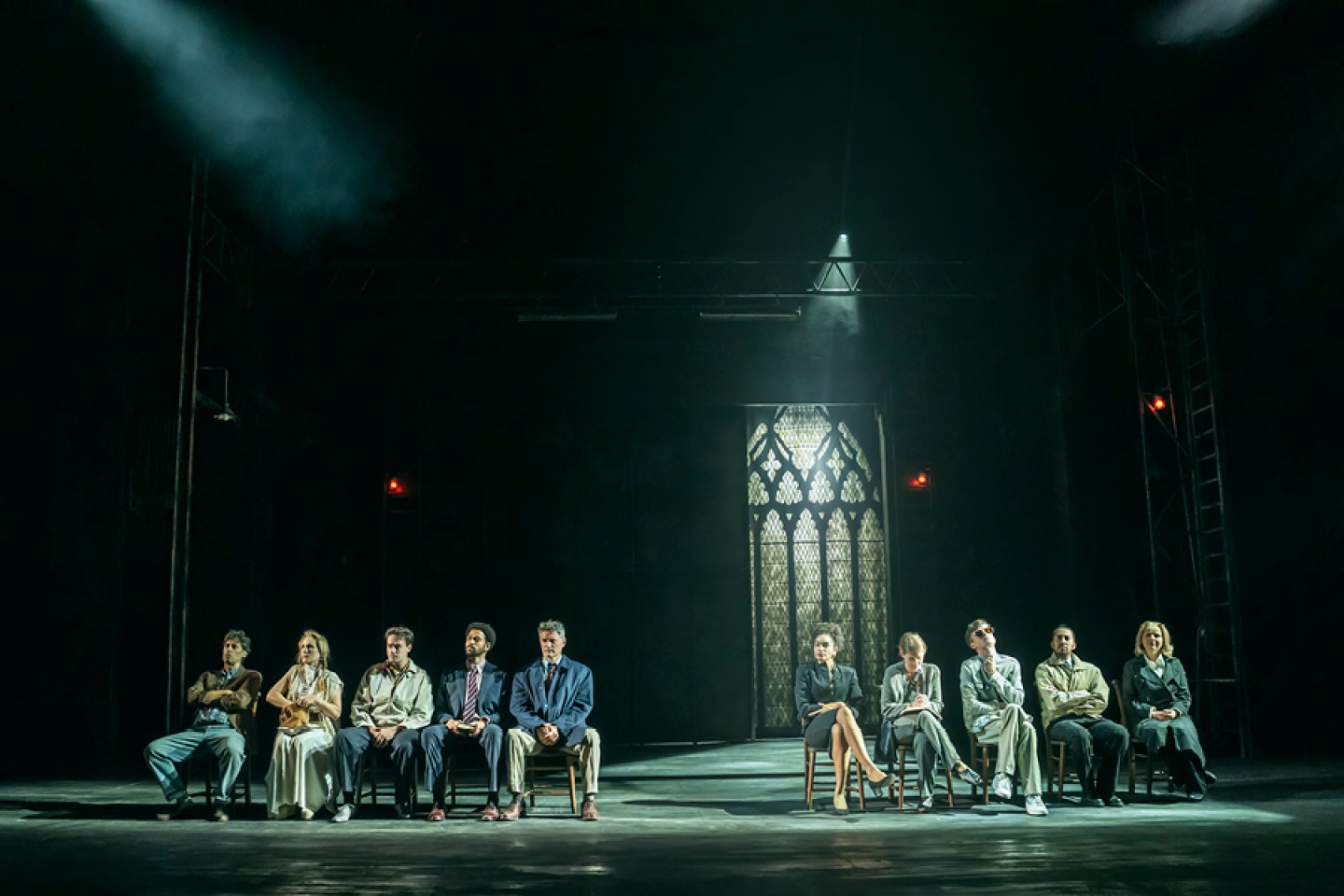 cast of inspector Morse sitting in a line 5 either side, on a dark stage with spot lighting 