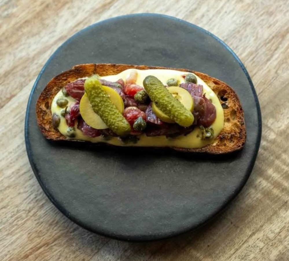Toasted bread topped with cheese meat and pickle