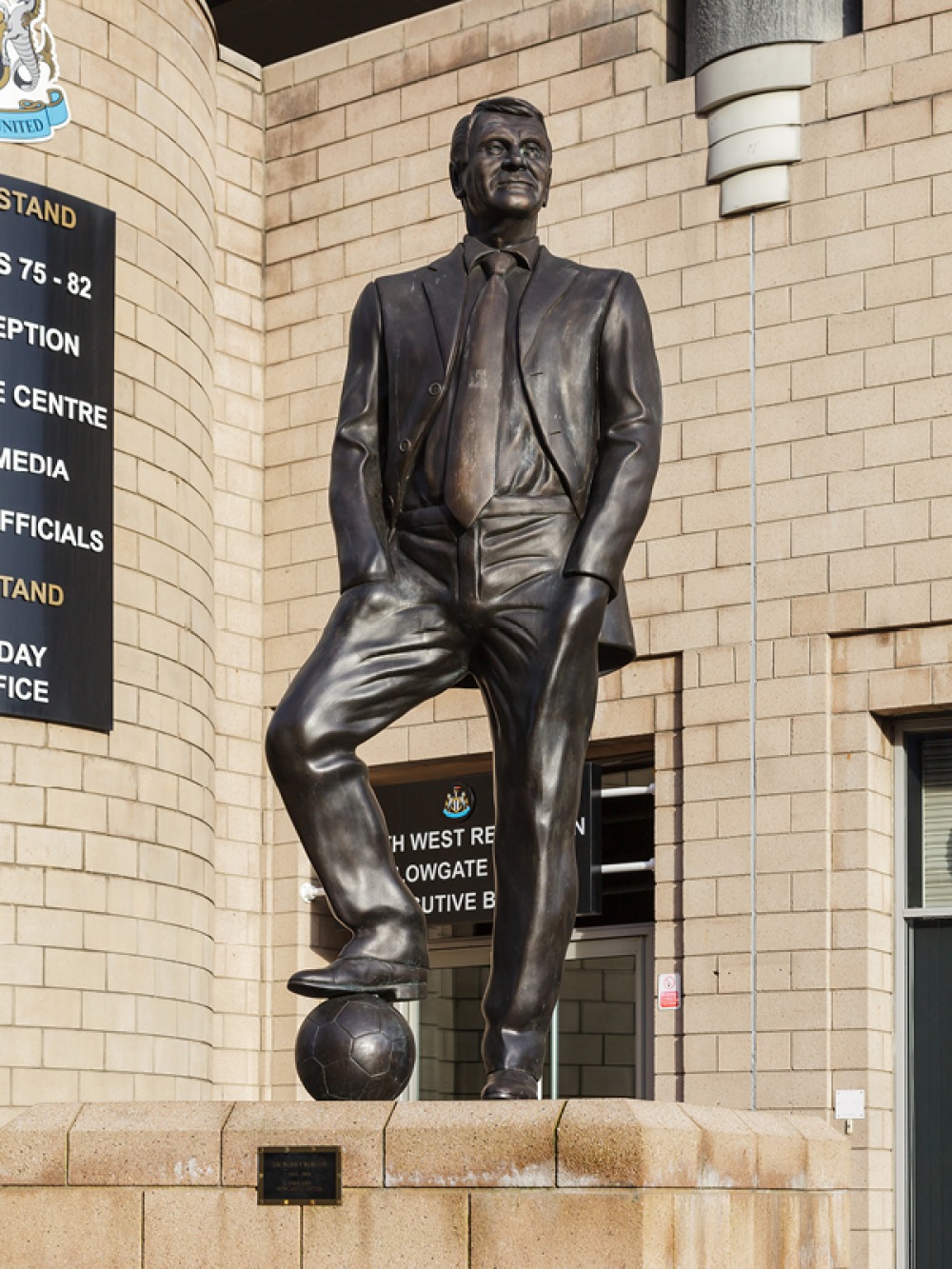 bronze statue of e man in a suit with a football