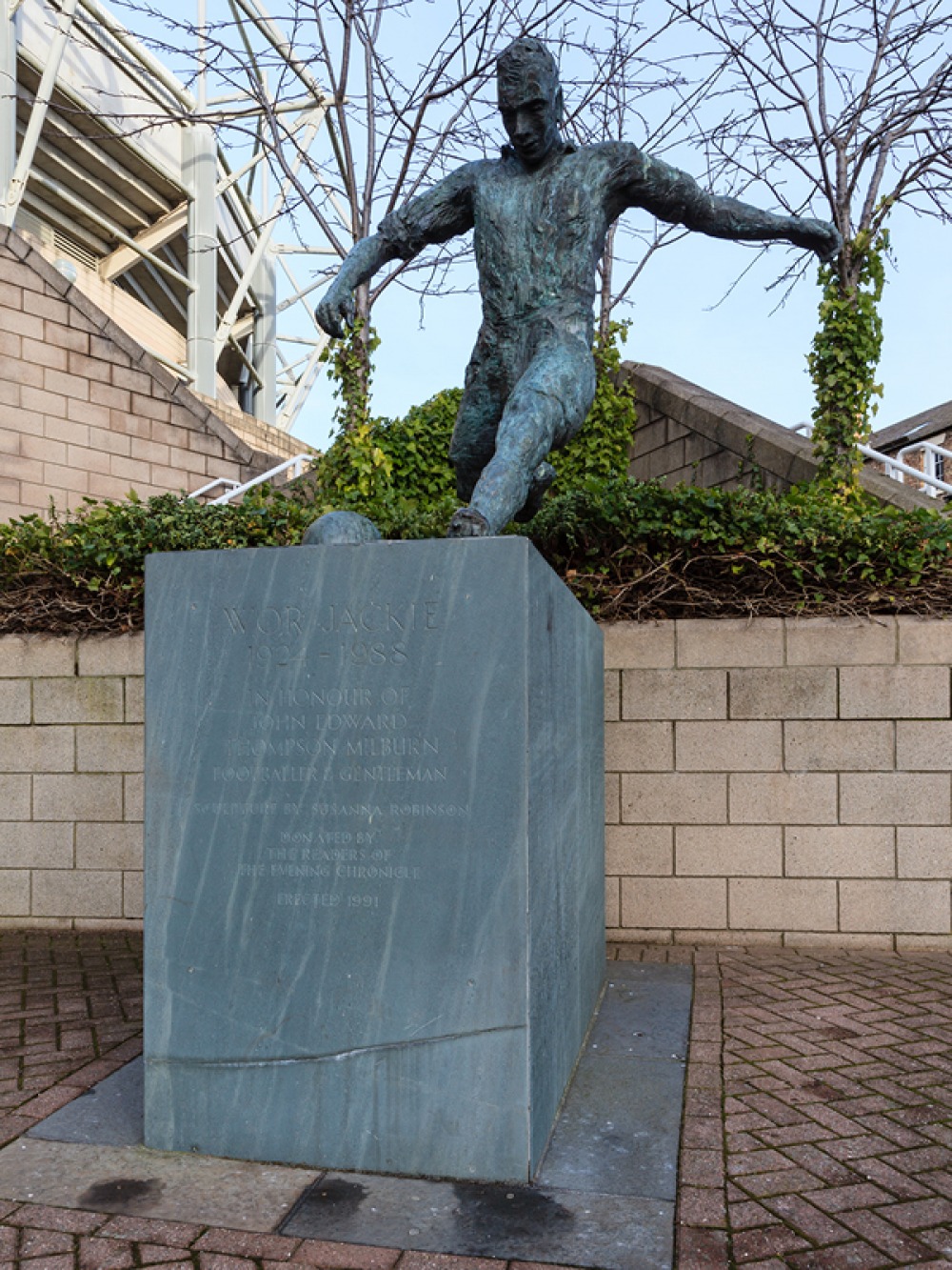 statue of a man kicking a football