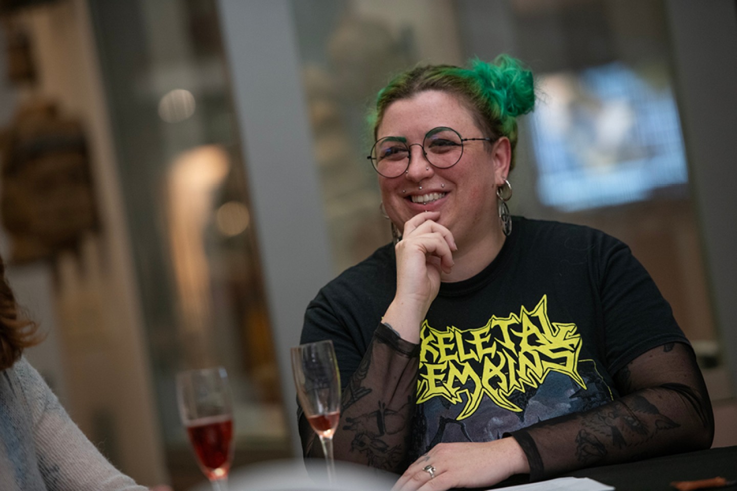 Woman with green hair in buns drinking a glass of fizz