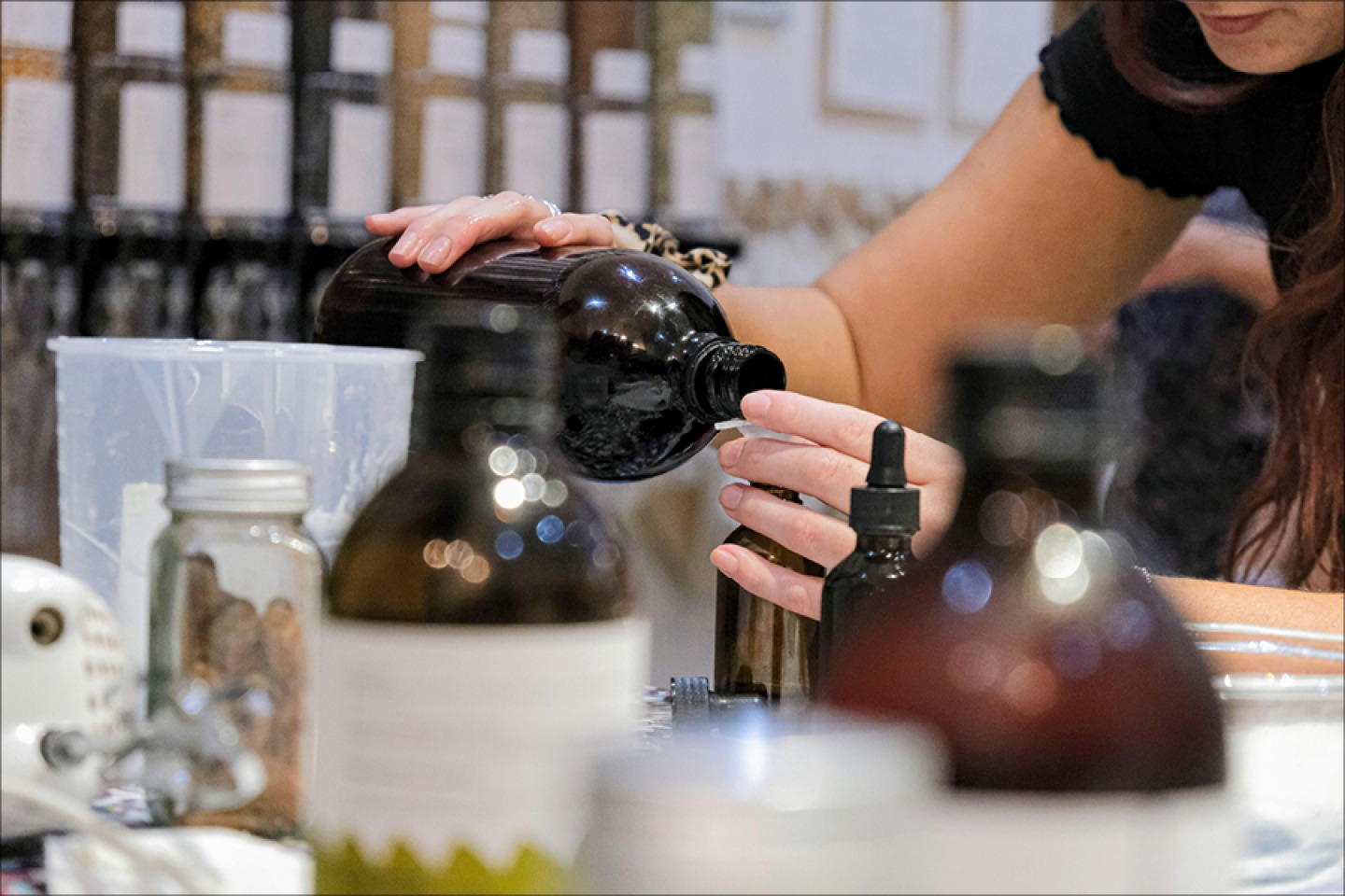 a woman pouring liquid into a bottle