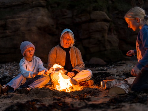 family on beach having a fire