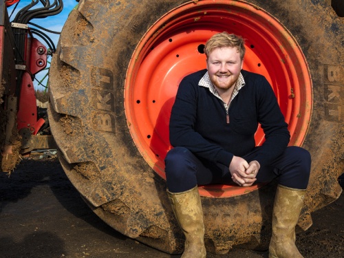 Man sat smiling in a tractor wheel
