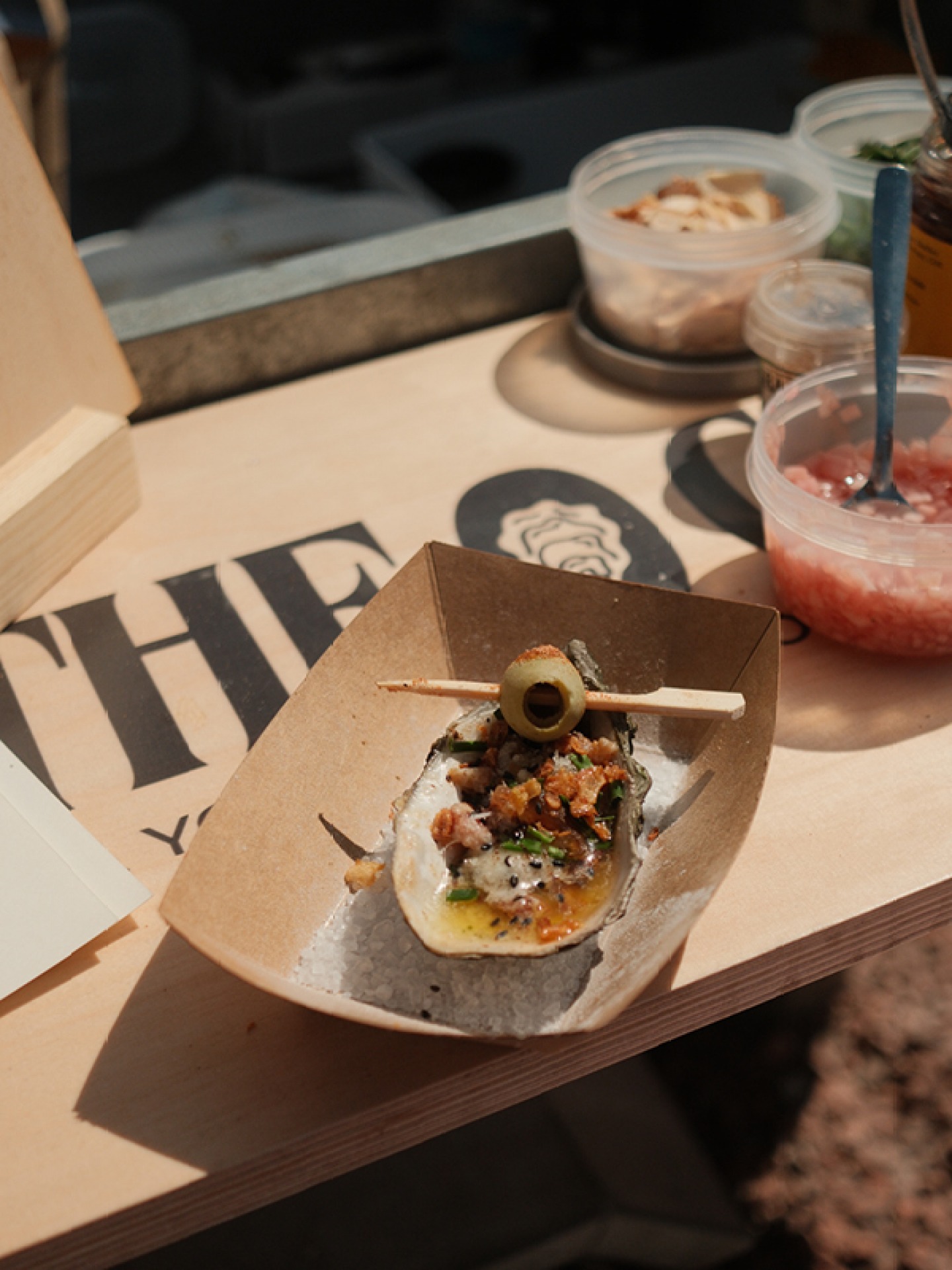 take away tray with a single oyster garnished with a olive